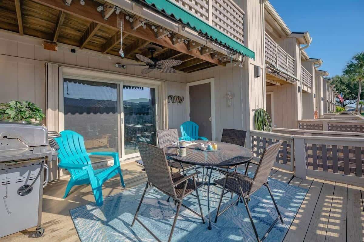Eine Terrasse im Freien mit Grill, türkisfarbenen Stühlen und einem Tisch mit Sitzgelegenheiten.