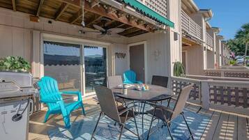 Eine Terrasse im Freien mit Grill, türkisfarbenen Stühlen und einem Tisch mit Sitzgelegenheiten.