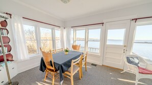 En matplats med ett bord och stolar, en bokhylla och utsikt över vattnet.