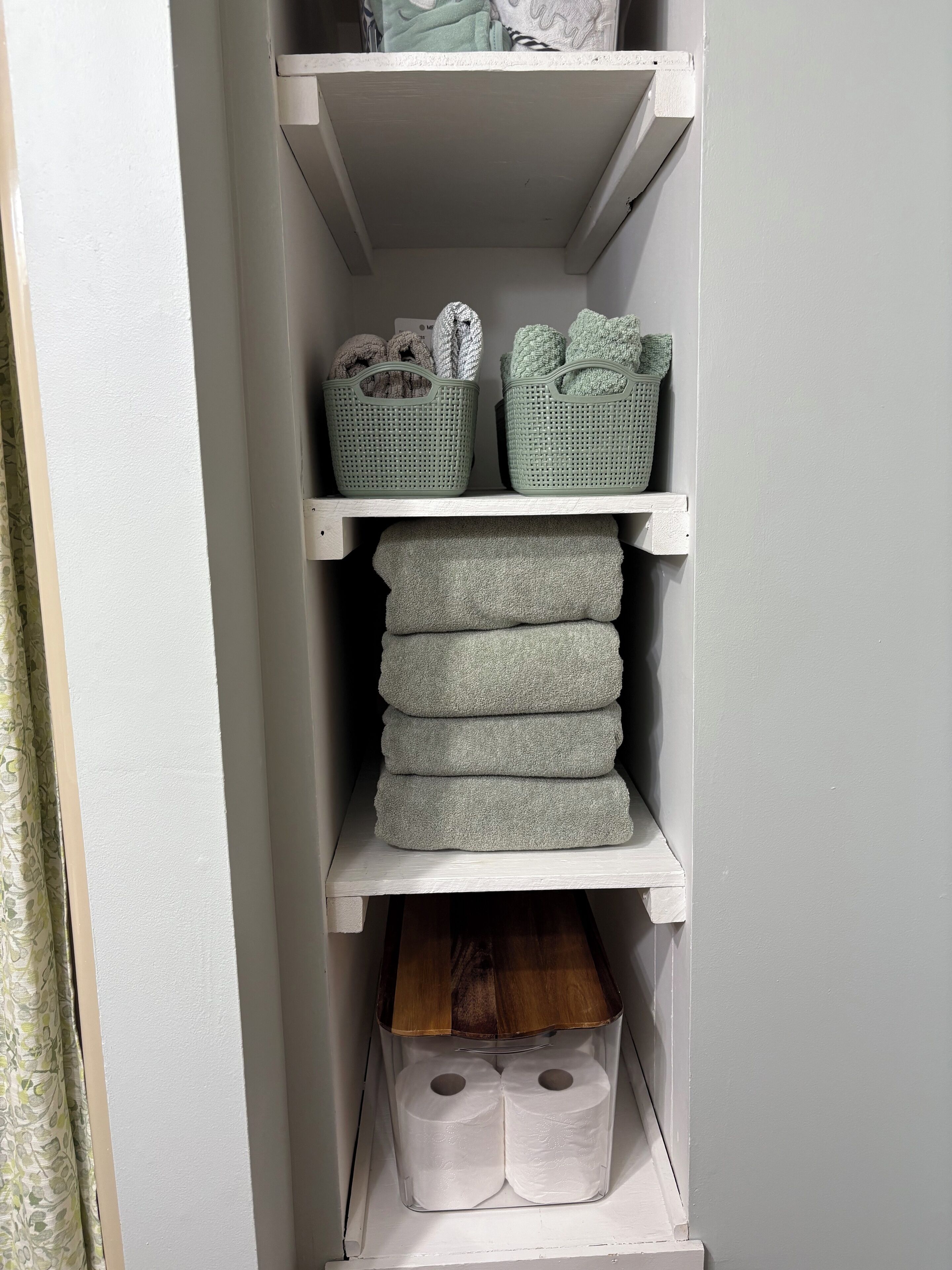 A storage unit with shelves holding baskets and folded towels.