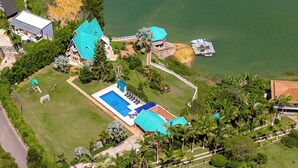 Une grande maison avec une piscine, un quai et un bateau.