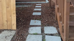 A backyard with a wooden deck, a concrete pathway, and a table with chairs. - Judkins Retreat - Close to Downtown (Seattle)