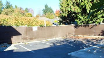Un espace de stationnement avec des places délimitées, une barrière en béton et un arbre en arrière-plan.