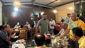Un ristorante con soffitto alto, luci a sospensione e un tavolo in vetro.