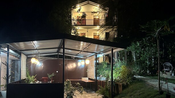 Una casa moderna con patio coperto, mobili da esterno e piante in vaso.