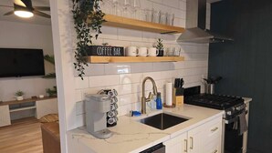 A modern kitchen with a coffee bar, a dishwasher, a stove, and a sink.