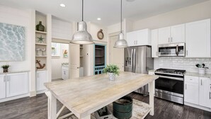 A modern kitchen with white cabinets, stainless steel appliances, and a wooden table. - North Winston Villa|Easy Beach Access|Private Pool & Golf Cart (Inlet Beach)
