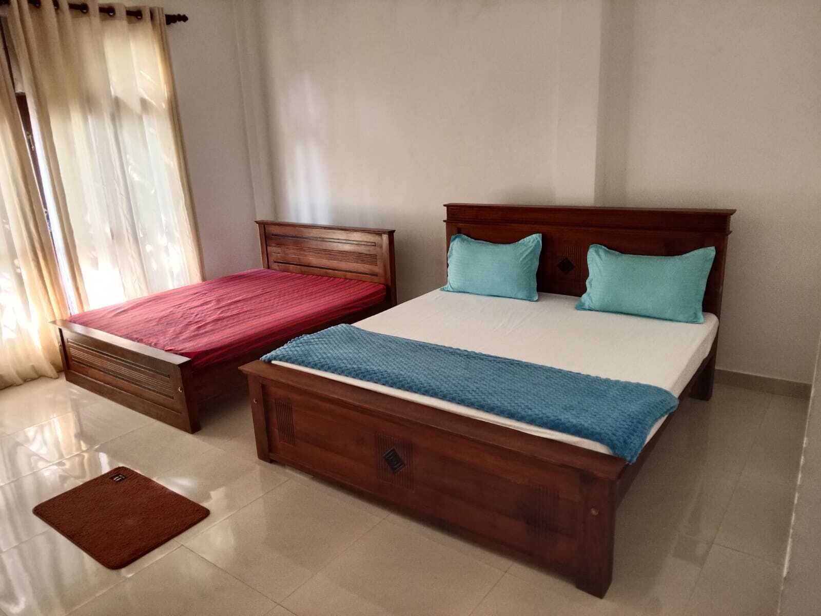 A bedroom with two single beds and a larger bed, all with wooden frames.
