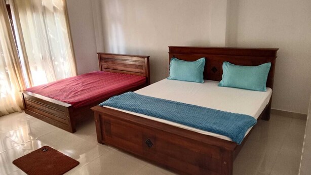A bedroom with two single beds and a larger bed, all with wooden frames.