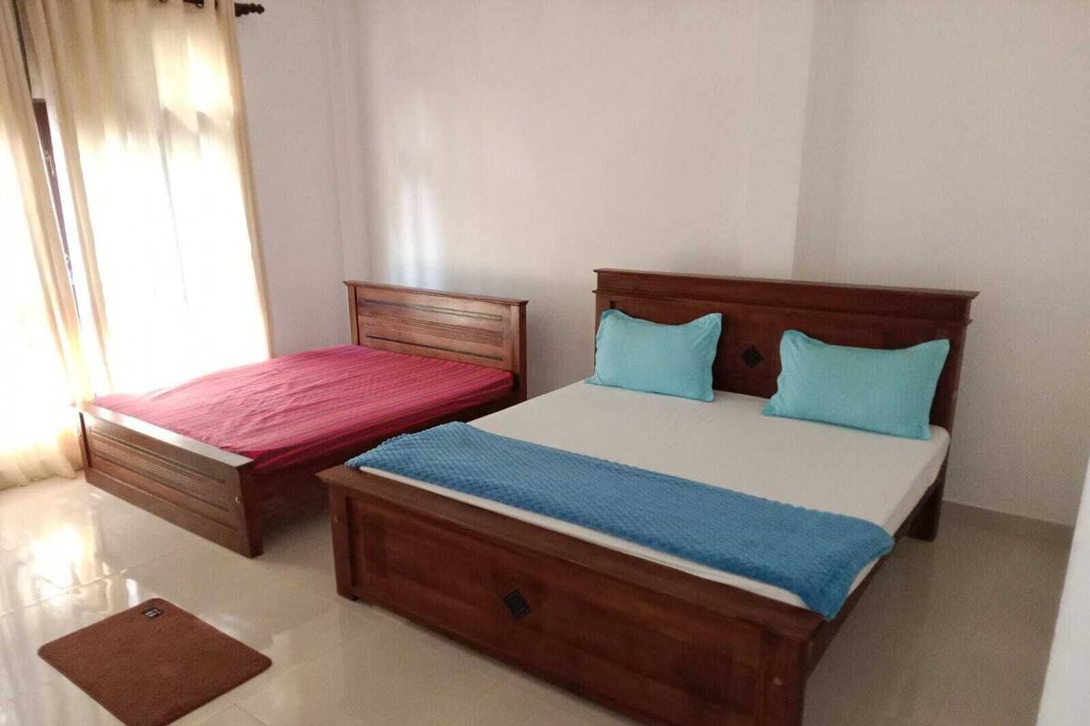 Une chambre avec deux lits, une tête de lit en bois et un petit tapis marron sur le sol.