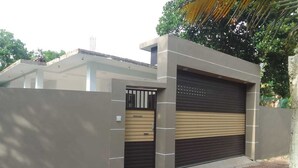 Un edificio moderno con puerta de garaje, entrada protegida por un portón y pared de hormigón.