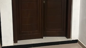 Puertas dobles con manija y cerradura, ubicadas en un pasillo con paredes blancas y suelo de baldosas.