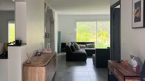 Een moderne woonruimte met een keukenhoek, een zithoek met een bank en een eettafel.