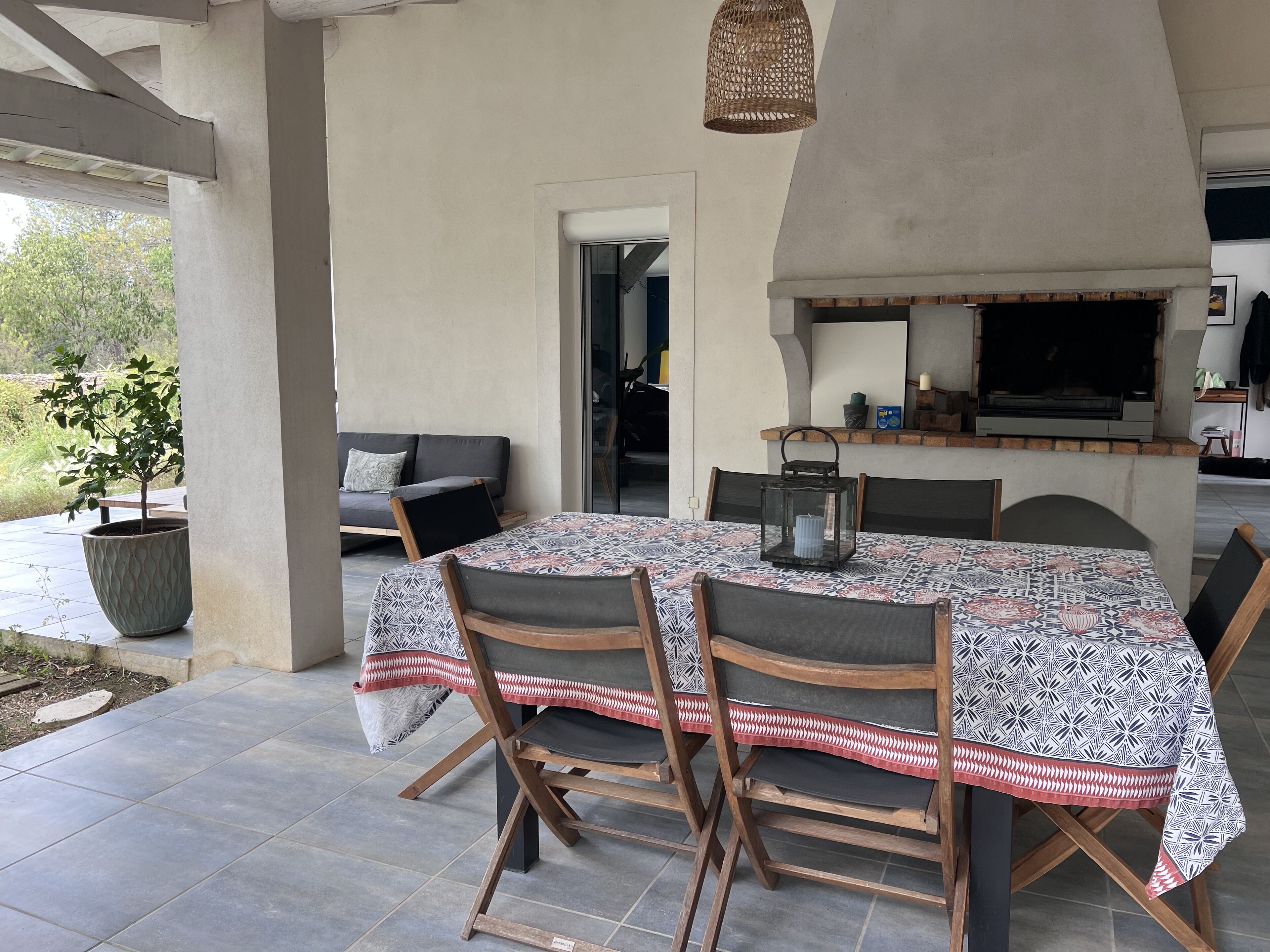 Une terrasse extérieure avec une table et des chaises, un canapé, une plante en pot et une cheminée.