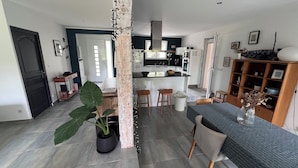 A modern kitchen with white cabinets, a central island, and a dining area with a table and chairs. - Family home with large pool and garden - Peace and quiet guaranteed (Aubais)