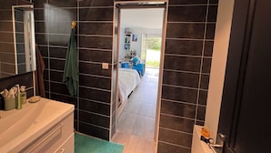 Een moderne badkamer met donkere tegels, een witte wastafel en een groene handdoek aan de muur.