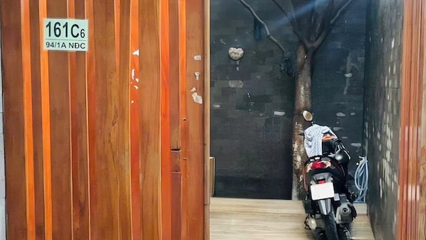A wooden gate with a sign, a motorcycle, and a tiled floor. - NAVILA homstay free laundry (Ho Chi Minh City)