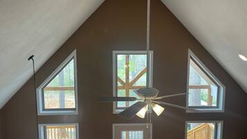 A room with a sloped ceiling, multiple windows, and a ceiling fan.