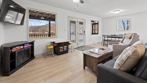 A spacious living area with a fireplace, a ceiling fan, and a dining area with a table and chairs.