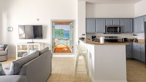 A modern living room with a grey sofa, a flat-screen TV, and a painting of a beach scene.