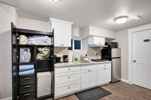 A compact kitchen with white cabinets, a black refrigerator, a microwave, and a coffee maker. - Judkins House - Close to Downtown (Seattle)