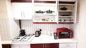 A compact kitchen with a gas stove, a kettle, a toaster, and a microwave.