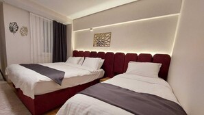 A hotel room with two beds, a large window with curtains, and a decorative wall piece.