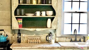 A rustic kitchen with wooden shelves, a sink, and a window. - Charming historic cottage in Enoree (Enoree)