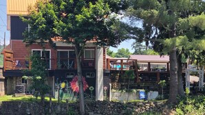 A lakeside view with a building featuring a stone wall and a wooden deck.