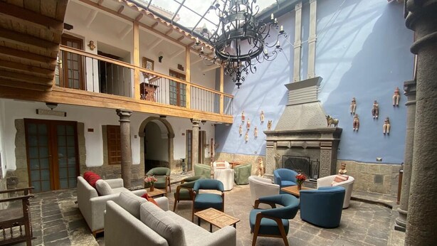 Un intérieur spacieux avec un plafond haut, une cheminée et un balcon doté de balustrades en bois.