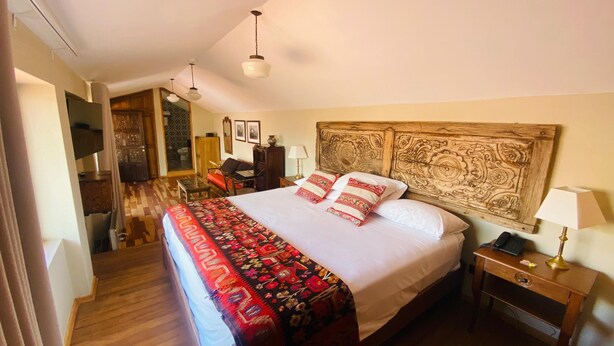 Een slaapkamer met een groot bed, een houten hoofdbord, een nachtkastje met een lamp en een bureau met een stoel.