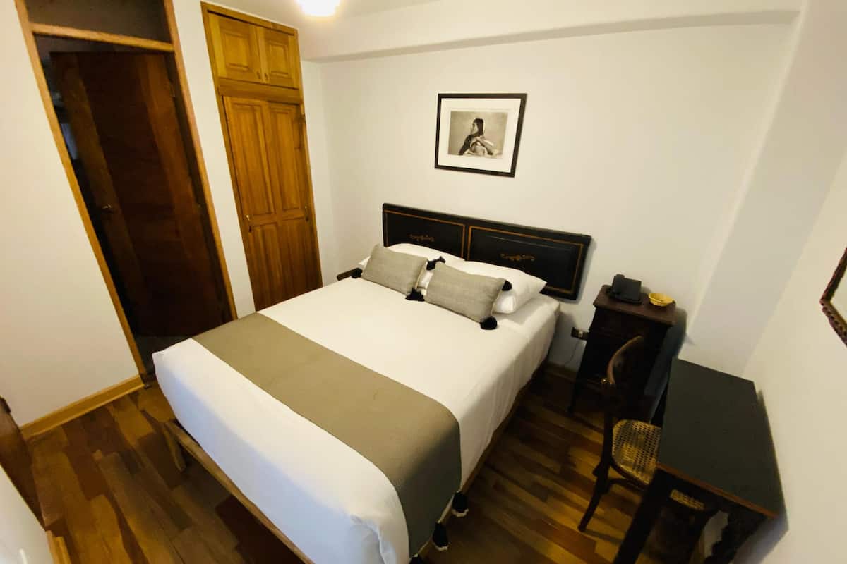 Un dormitorio ordenado con cama, escritorio y silla.