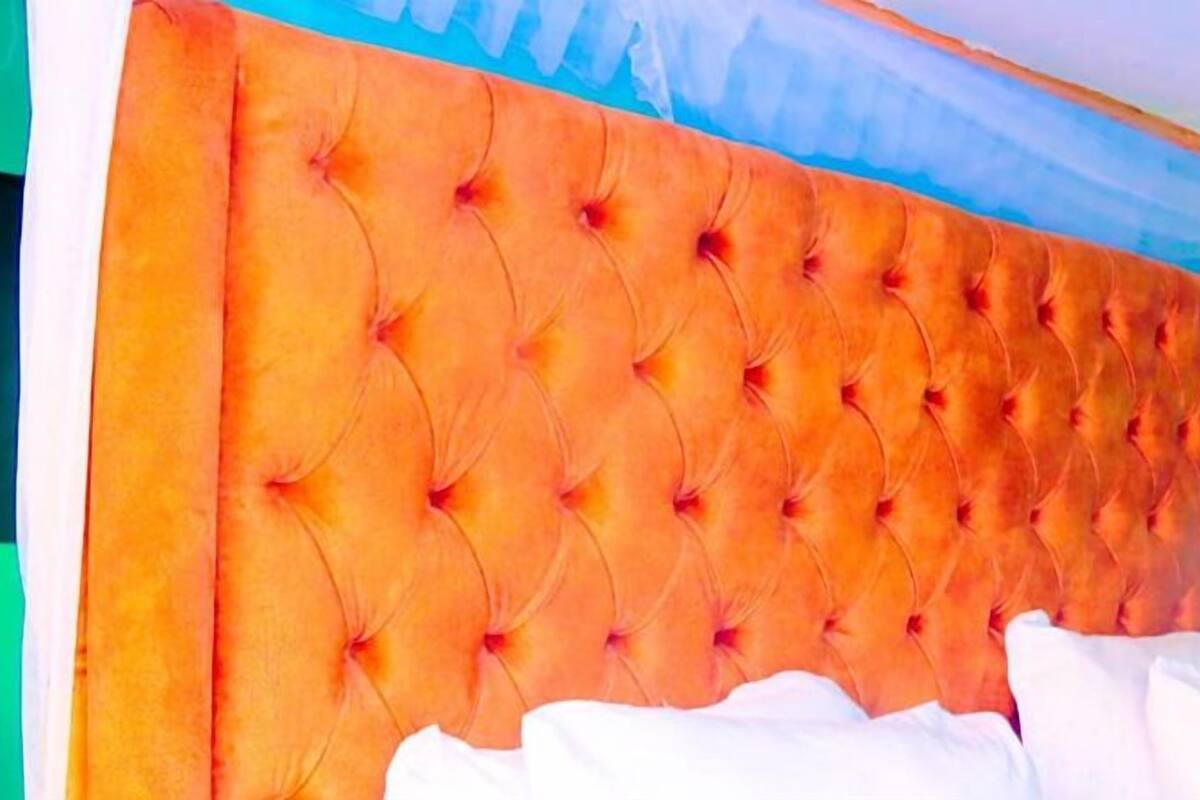 A bed with a tufted headboard in a room with green walls.