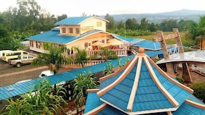 A hotel with a blue-roofed structure, a swimming pool, and a view of the surrounding landscape. - Maya Holiday Point Kisii (Ogembo)