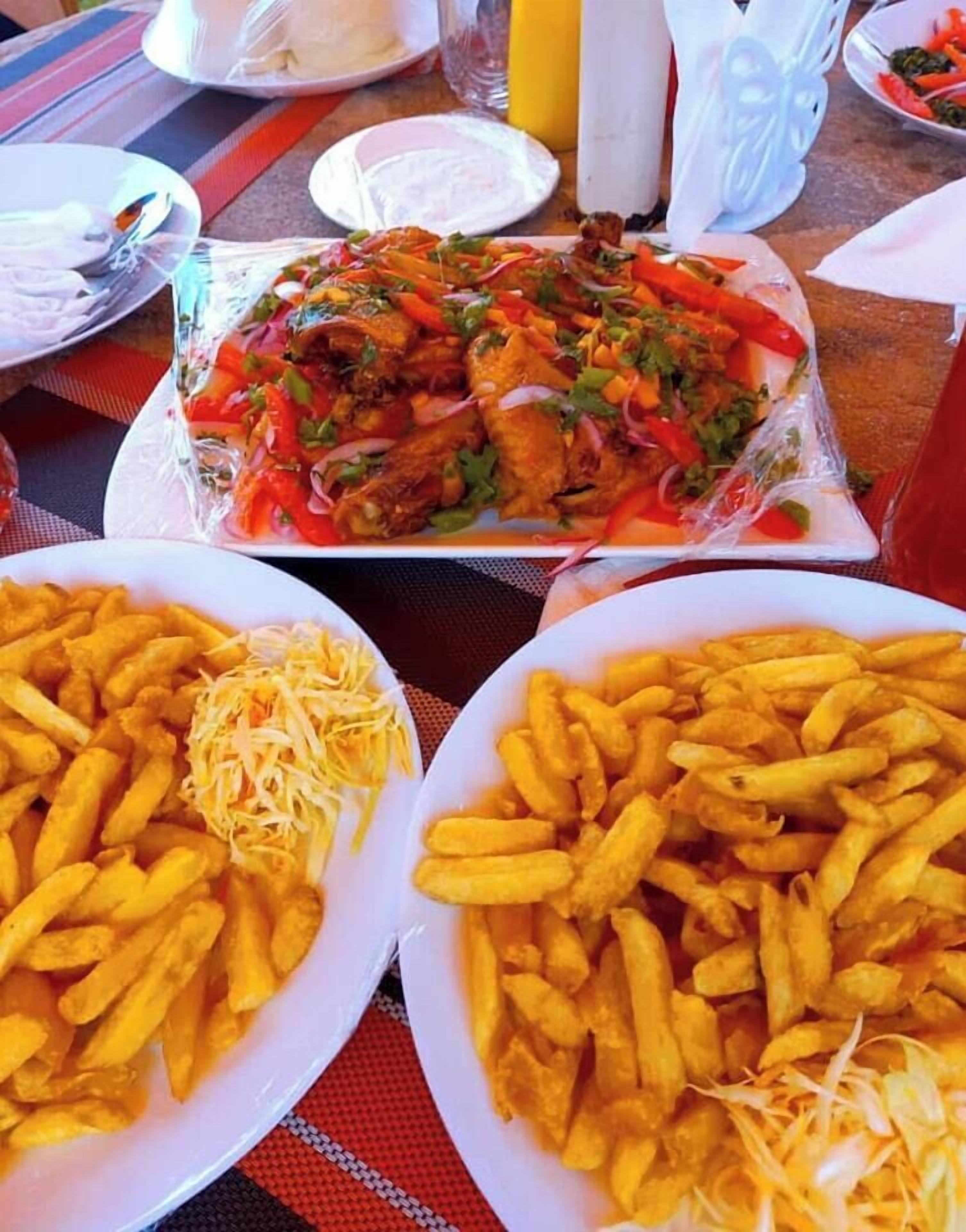 A table with plates of food, including fries and a dish with vegetables and meat.