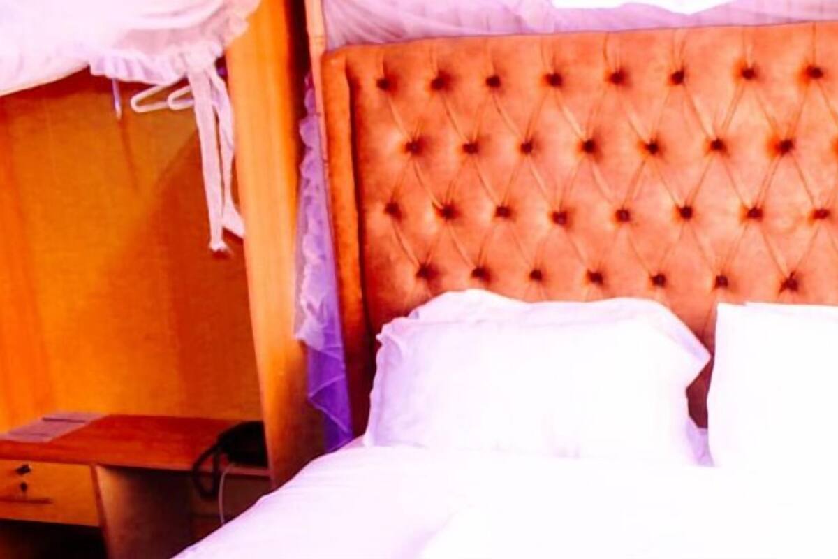 A room with a tufted headboard, a wooden nightstand, and a bed with white bedding.