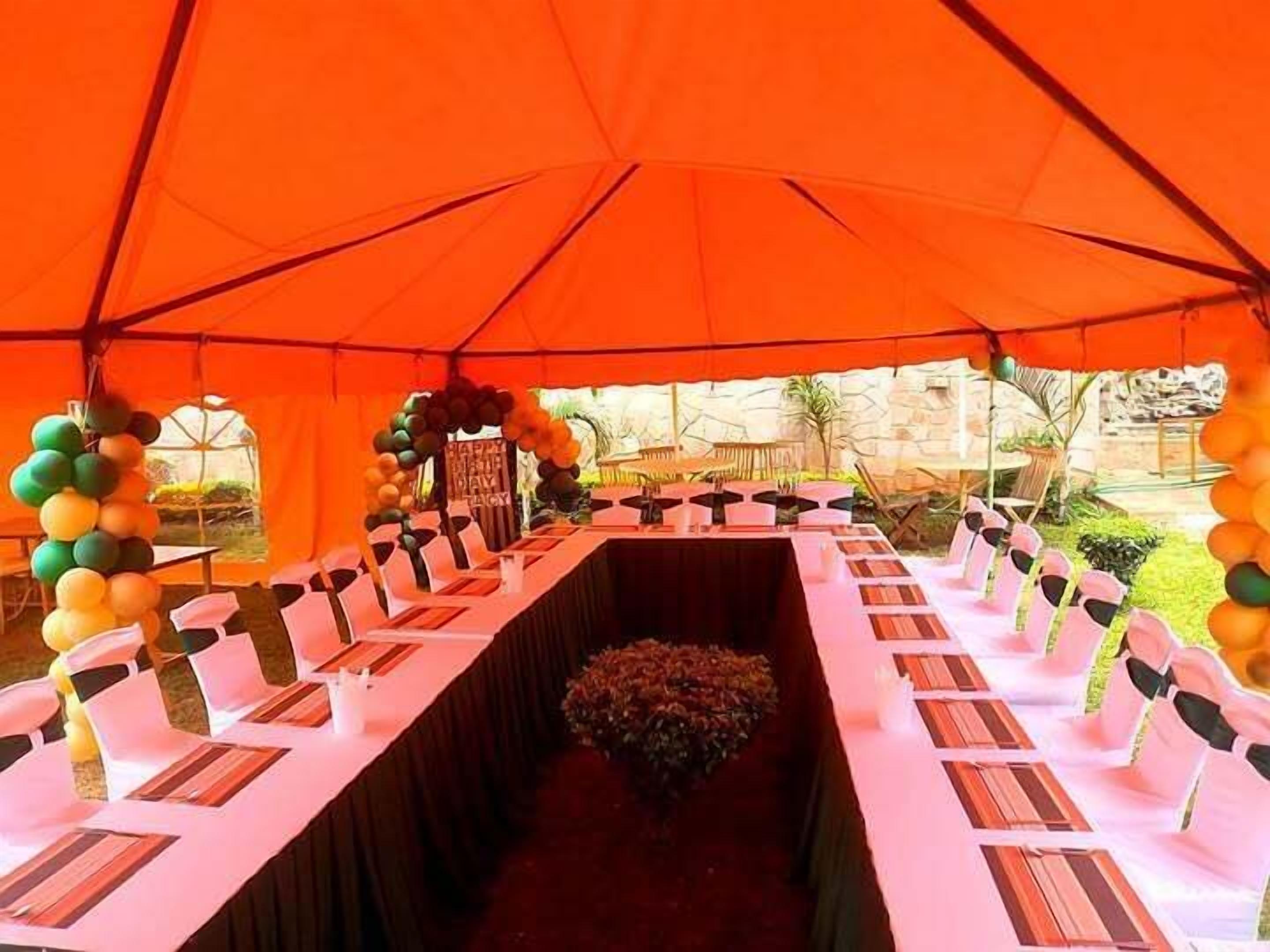 A tented outdoor event space with tables set up for dining, surrounded by balloons and a floral arrangement.