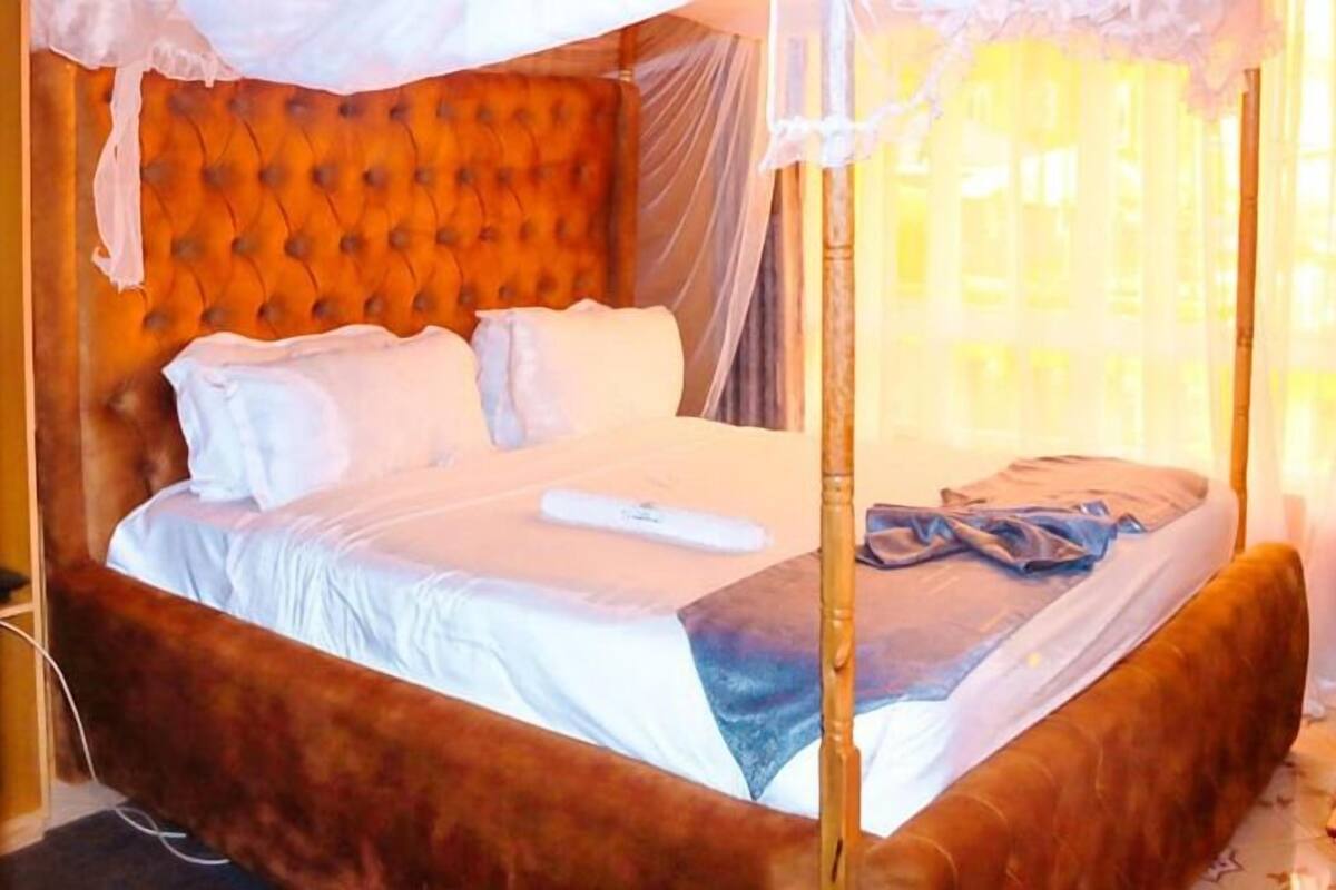 A bed with a canopy, a wooden headboard, and a bedside table with a lamp.