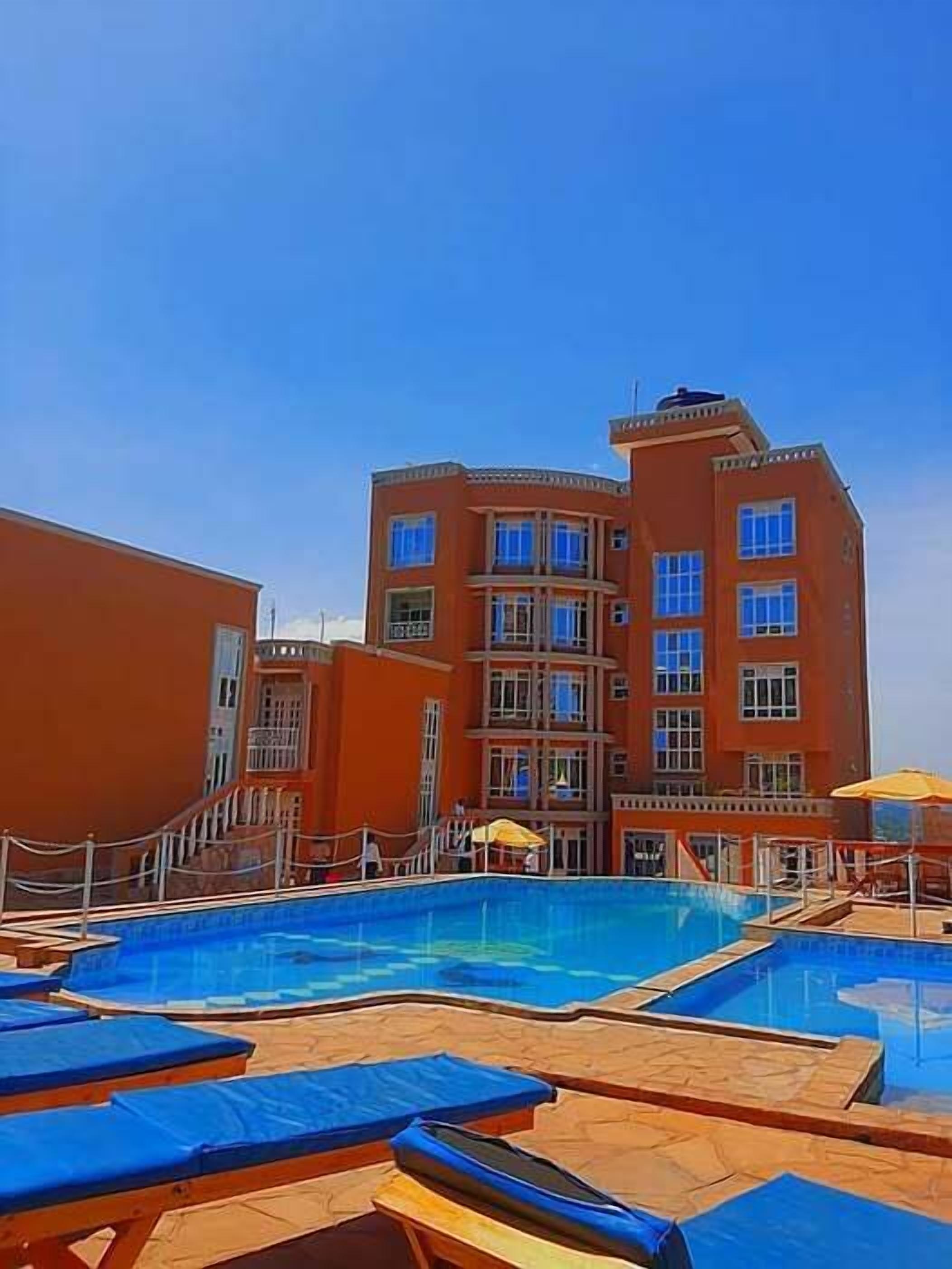 Un hôtel doté d’une piscine, de plusieurs balcons et offrant une vue sur un ciel d’un bleu limpide.