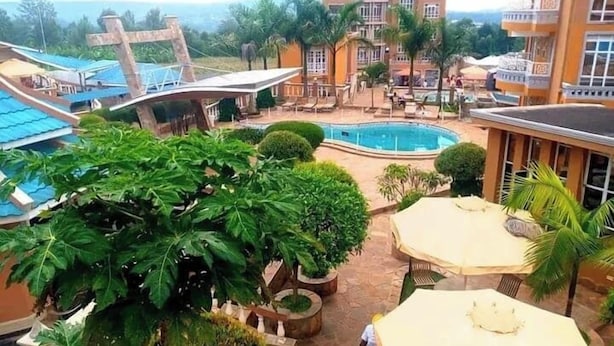 A hotel with a pool, outdoor seating, and lush greenery. - Maya Holiday Point Kisii (Ogembo)