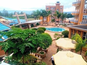 A hotel with a pool, outdoor seating, and lush greenery. - Maya Holiday Point Kisii (Ogembo)