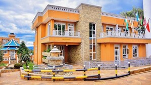 A hotel with a stone facade, a fountain, and a balcony with flags. - Maya Holiday Point Kisii (Ogembo)