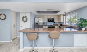 A modern kitchen with a central island, stainless steel appliances, and a window with blinds. - Family friendly oasis 4 bedrm 2 bathrm 4 beds (Mesa)