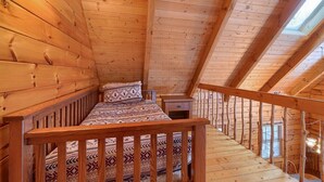 A wooden cabin bedroom with a bed, a nightstand, and a window.