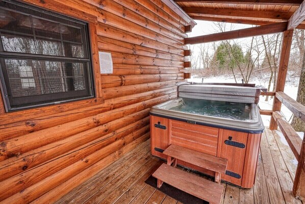 Eine Holzhütte mit Whirlpool auf einer Holzterrasse.