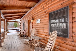 A wooden cabin with a covered porch, rocking chairs, and a sign that reads "Woods Edge." - Woods Edge Cabin | Hocking Hills, Hot Tub, Pets (Logan)