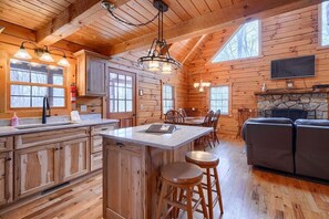A log cabin interior with a kitchen, dining area, and living room.