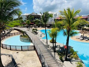 A resort with a circular pool, a wooden deck, and palm trees.