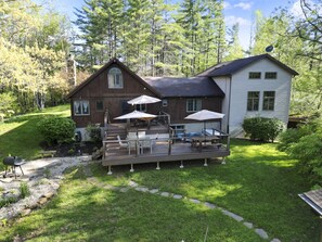 Une maison à deux étages dotée d’une terrasse, de mobilier d’extérieur et d’une antenne parabolique.
