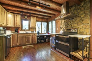 A kitchen with wooden cabinets, a stone wall, and a large stove.